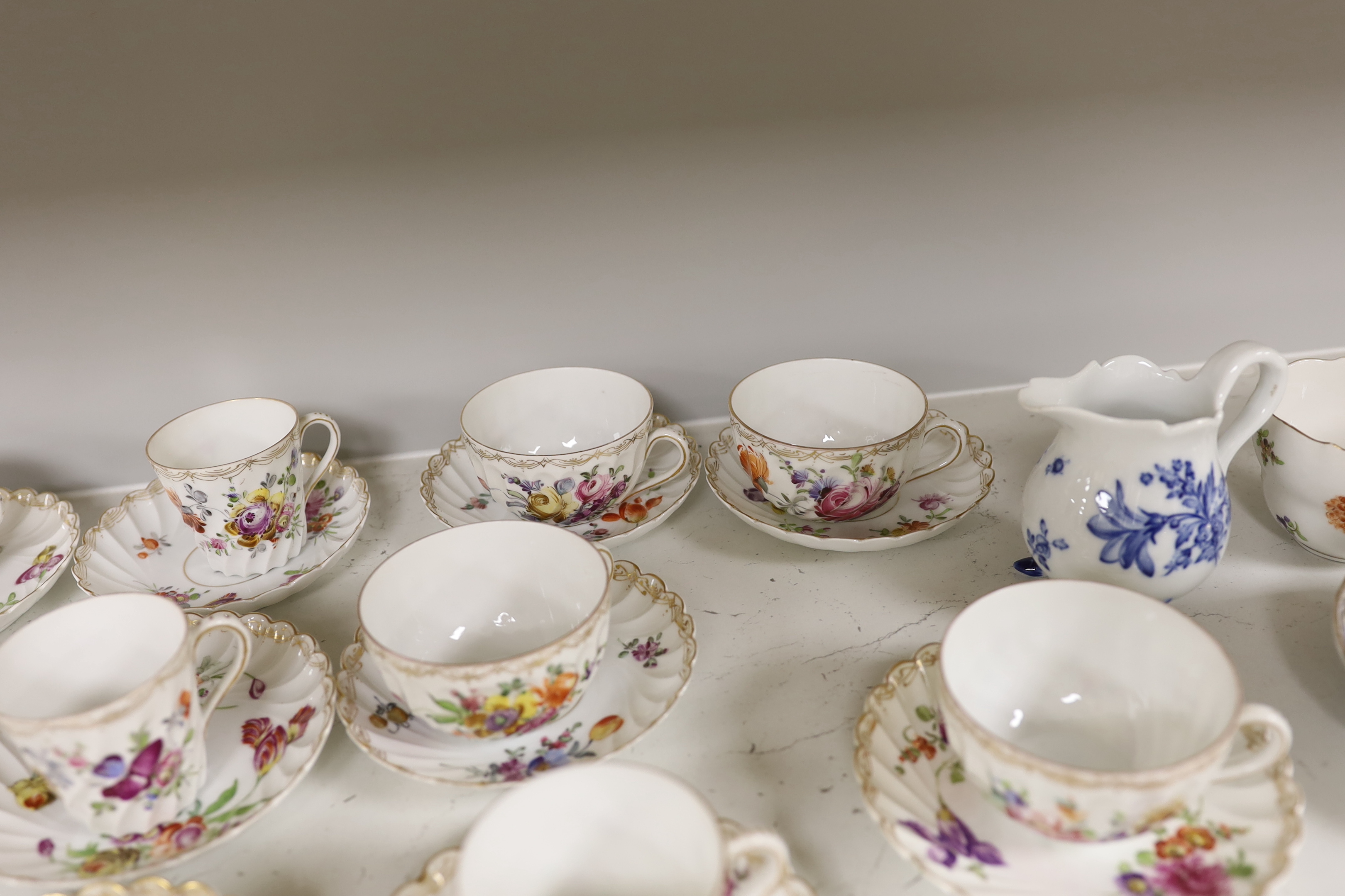 A group of porcelain Dresden tableware including cups and saucers and a blue and white jug
